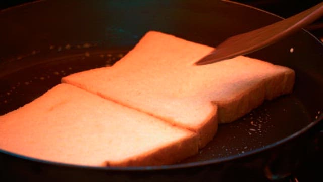 Toast being prepared with bread and butter in a frying pan