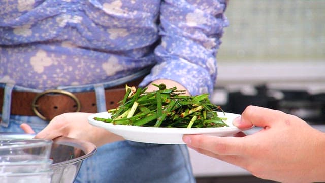 Three people making chive salad together in the kitchen