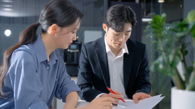 Two colleagues discussing documents in an office