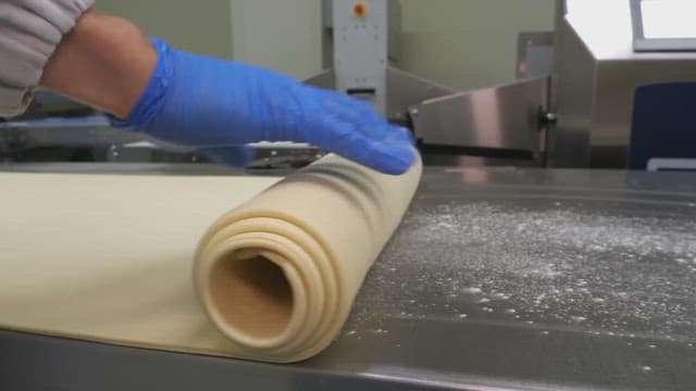 Wworker rolling out dough with precision