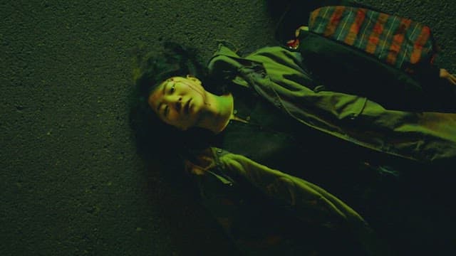 Woman lying on the street at night with her head bleeding