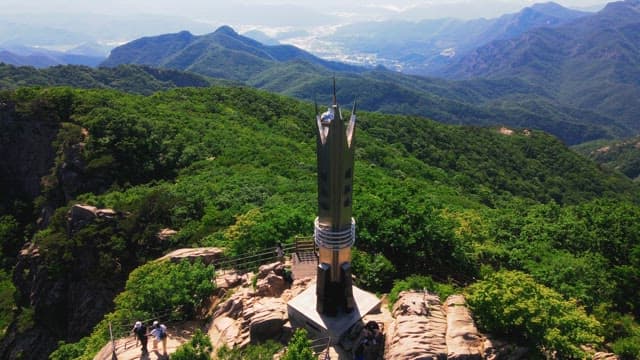 Tower located on the top of a mountain where hikers are present.