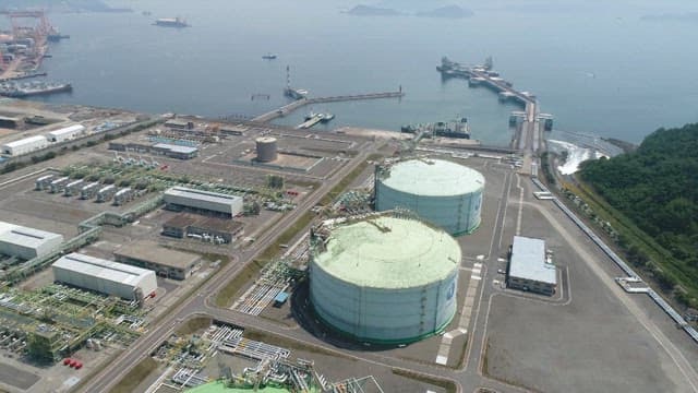 Industrial facility near the sea with large storage tanks and docking stations