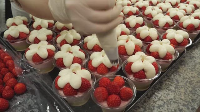 Decorating strawberry dessert with cream in the kitchen