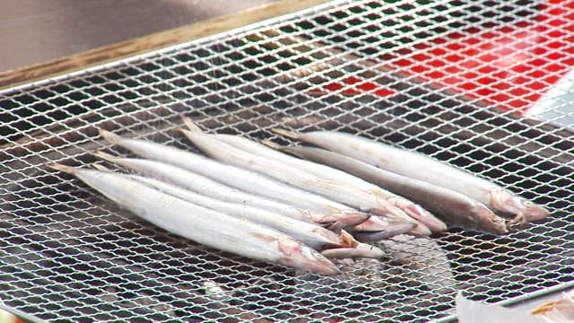 Salting saury on an outdoor grill