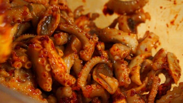 Mixing spicy seasoning and octopus in a glass bowl