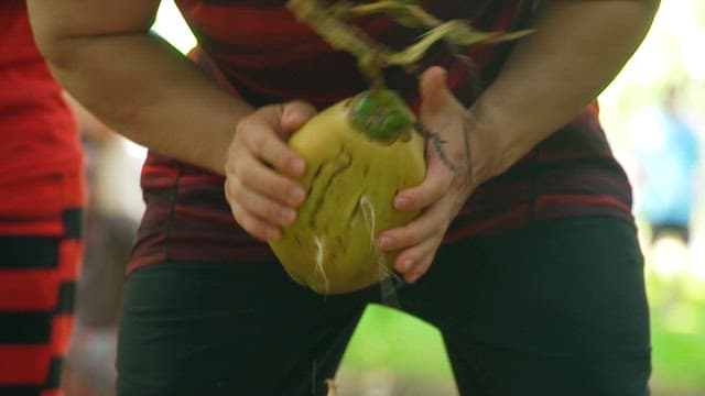 Person preparing a coconut outdoors