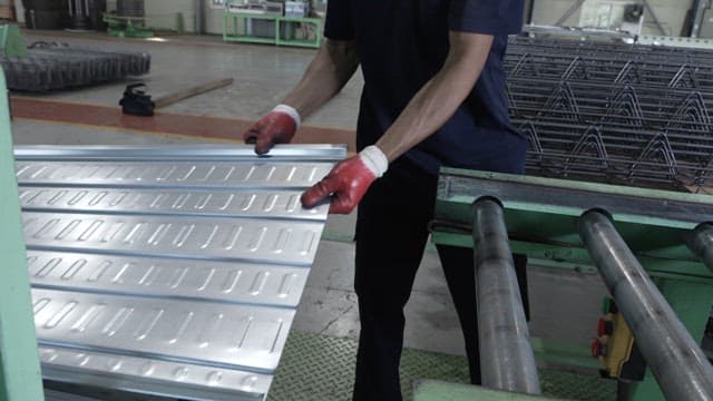 Worker handling metal sheets in a factory