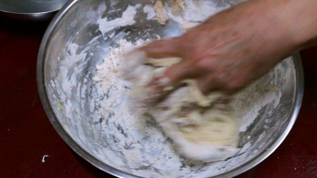Hand kneading dough in a metal bowl