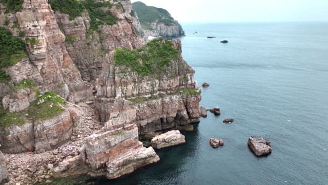 Coastal area with Baeknyeongdo Island sign on cliff on a cloudy day