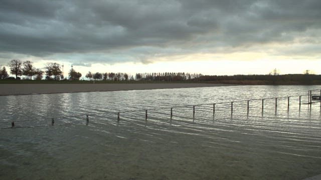 Tranquil lakeside landscape reflecting under a cloudy sunset sky