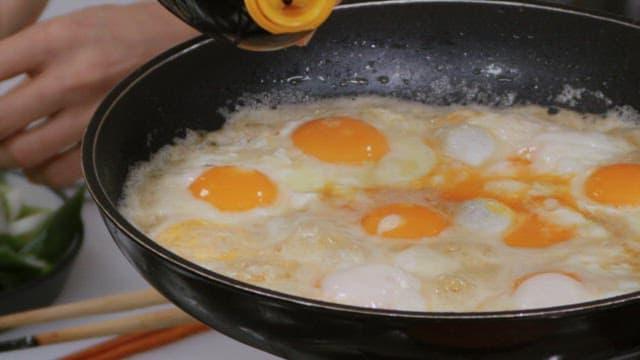 Cooking savory fried eggs in a frying pan with sesame oil