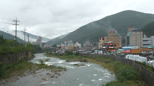 Small town nestled between green mountains with rising smoke