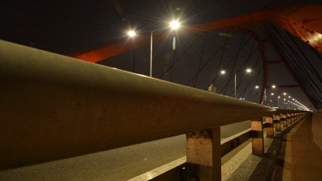 Trace of car lights passing over a bridge lit at night