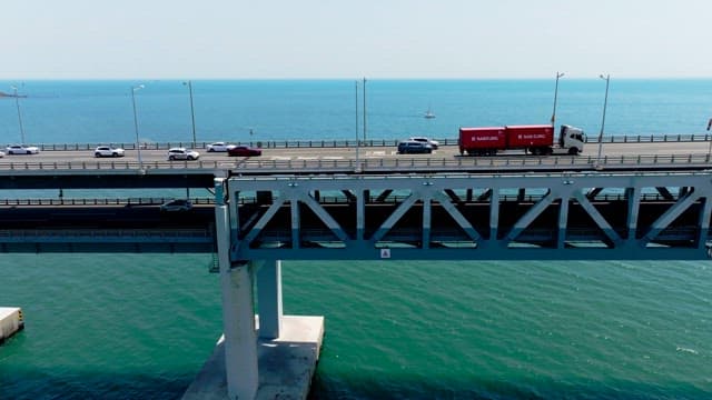 Vehicles crossing a Gwangan Bridge over the calm sea on a clear day