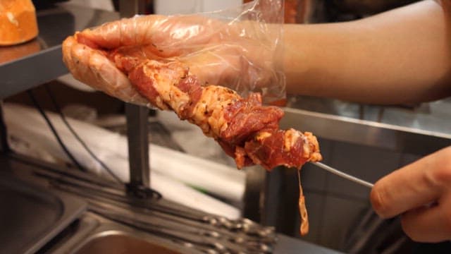 Skewering Raw Marinated Meat in a Kitchen