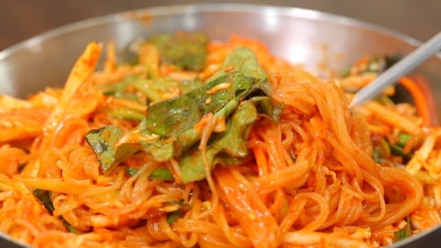 Chopstickful of delicious bibim jjolmyeon with fresh vegetables