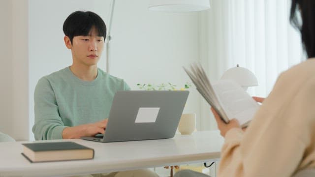 Man using laptop at living room table in bright interior