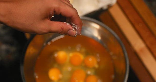 Adding Salt to Eggs in a Bowl