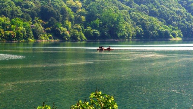 People rowing a small boat on a blue lake