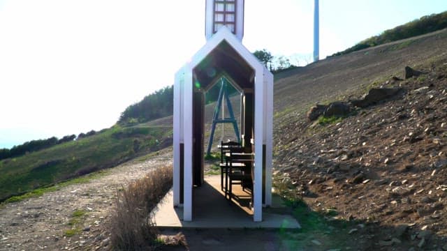 Model of a small chapel on a hillside with bright sunlight and clear blue sky