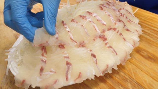 Fresh raw fish neatly arranged on a plate on a wooden cutting board