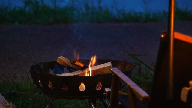 Roaring firewood in a brazier on the grass in the evening