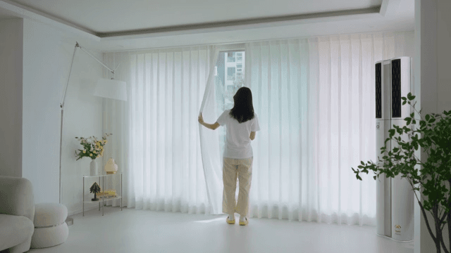 Woman opening curtains in modern living room in white interior