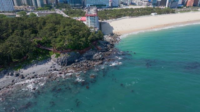 Beach with cliffs and green forests of coastal town