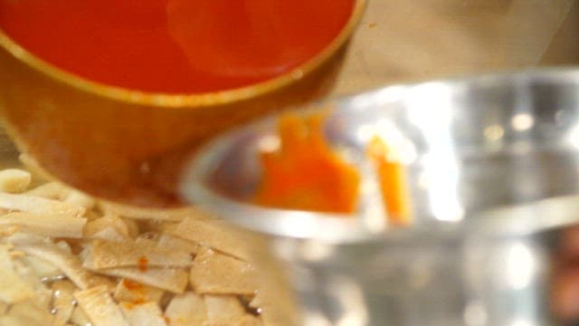 Preparing fish cakes in broth with gochujang