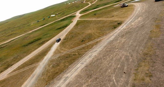 Car driving on a dirt road in open fields