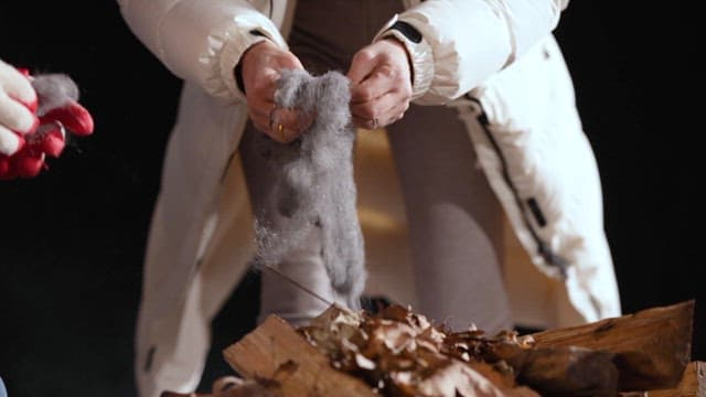 People Preparing a Campfire with Firewood at Night