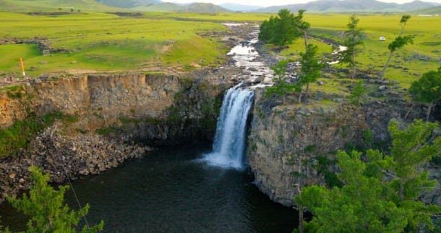 Scenic waterfall in a vast green landscape
