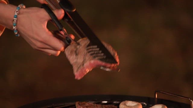 Grilling beef steak and mushrooms on a barbecue grill