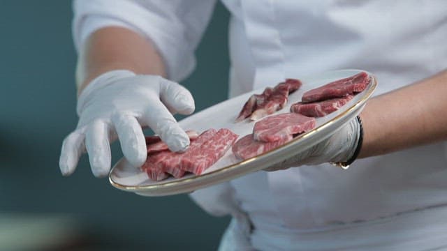 Chef presenting a plate of raw beef
