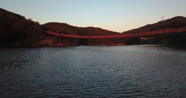 Red bridge over a serene lake at sunset