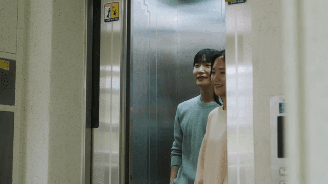 Two people getting out of the elevator in an apartment building