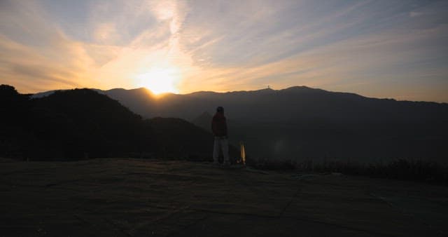 Contemplative Person Watching Sunrise in Mountains