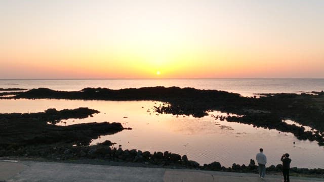 Sunset over a rocky beach with calm waters