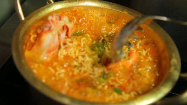 Appetizing seafood ramen with red crab boiling in a pot