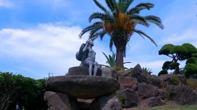 Statue sitting among tropical plants and rocks