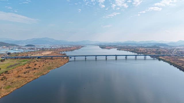 Wide river with a bridge and distant mountains