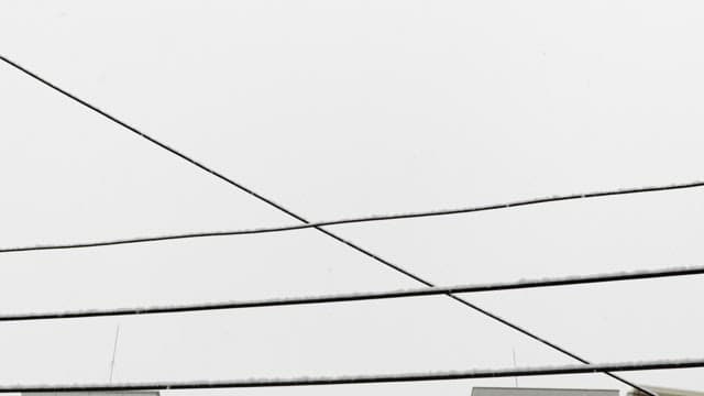 Wintery power lines crossing a snowy sky