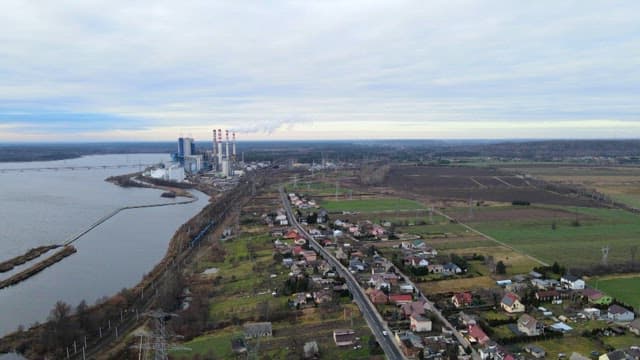 Peaceful riverside village surrounded by industrial complexes