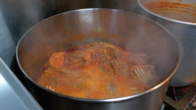 Pig's feet being boiled in a large steaming pot