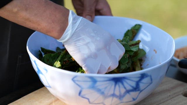 Close-up of hands mixing a fresh salad in a sunny outdoor setting.