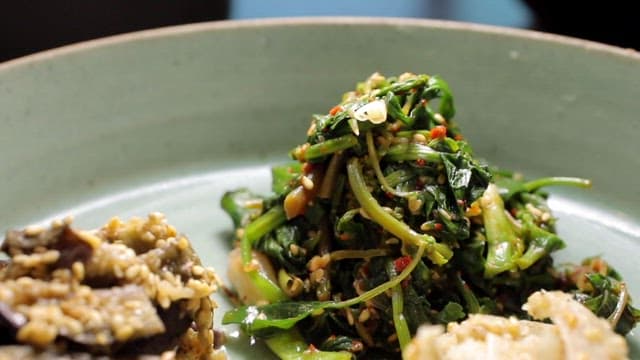 Variety of seasoned vegetables including stir-fried eggplant and seasoned bellflower root on ceramic plate