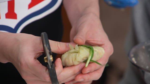 Cutting chives wrapped around cabbage rolls with scissors