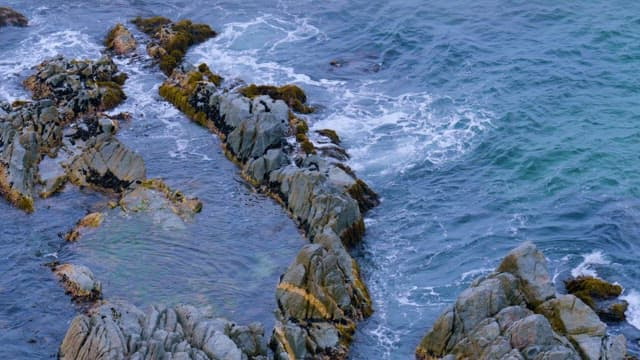 Waves Crashing against Steep Rocks on the Beach