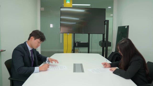 Business meeting in a conference room with two people signing documents.
